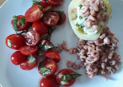 Salade de tomates cerises et pommes de terres garnies de crevettes grises.